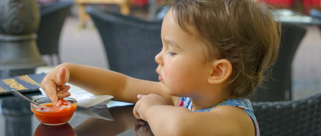 Little girl eating tomato sauce