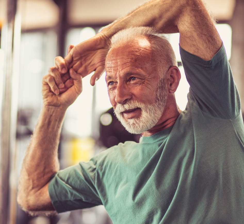 A senior man stretches in the gym