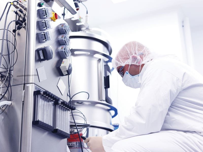 Person with protective equipment working on biopharma tanks
