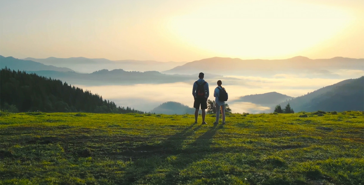 A man and his son admire a beautiful landscape at sunset.