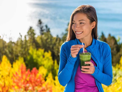 Woman drinking a smoothie with a forest in the background