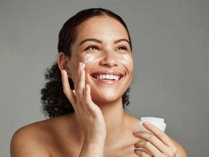 Young woman applying cream on her face