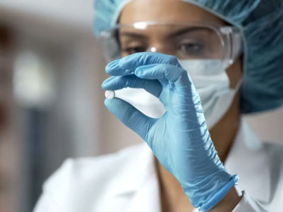 Scientist with a hairnet, gloves, a mask, and protective glasses holding a tablet in her hands