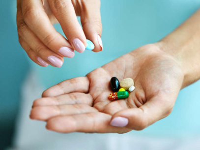 A woman is holding medicines in her hand.