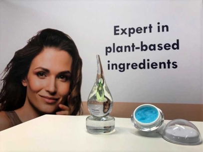 Glass award and open jar with blue powder on a counter, banner reads  Expert in plant-based ingredients. 