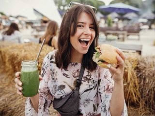 Woman eating a burger with a smoothie in her hand