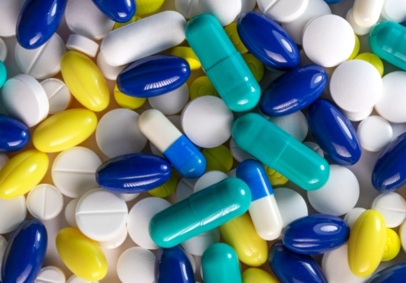 Various tablets, soft gels and capsules in white, blue and yellow