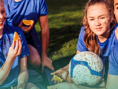 Teenage football players eating fruit slices on a soccer field