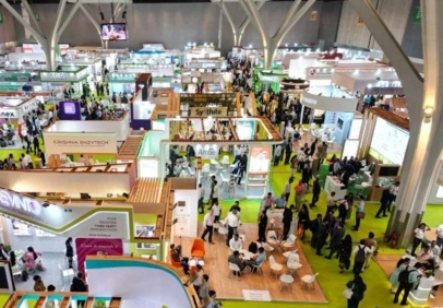 Crowded exhibition hall with multiple booths, visitors walking and networking at a large trade show.