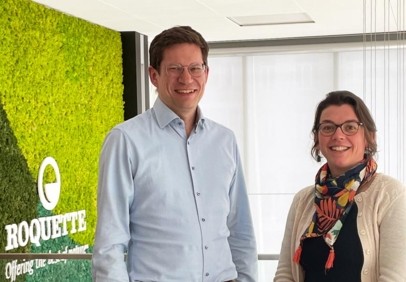 Two sustainability team members in front of a green moss wall with Roquette logo.