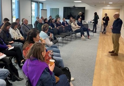 Des collaborateurs écoutent un manager qui se tient à l'avant de la salle lors d'une session de formation.