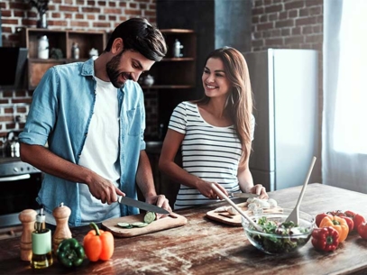 Man and woman preparing vegetables together in a modern kitchen.