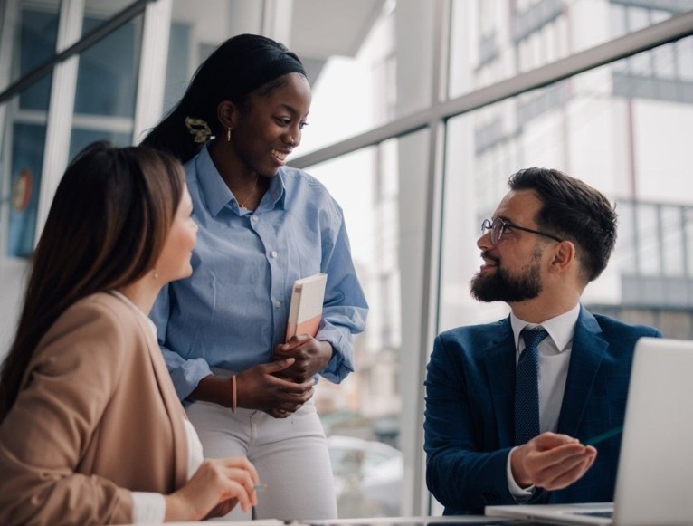 Three businesspeople talking in modern office environment.