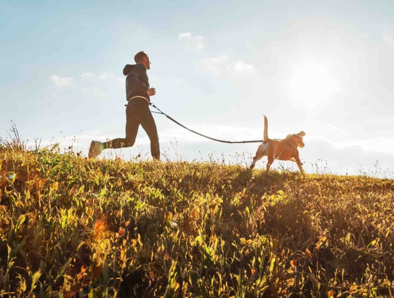 men running with his dog in a field