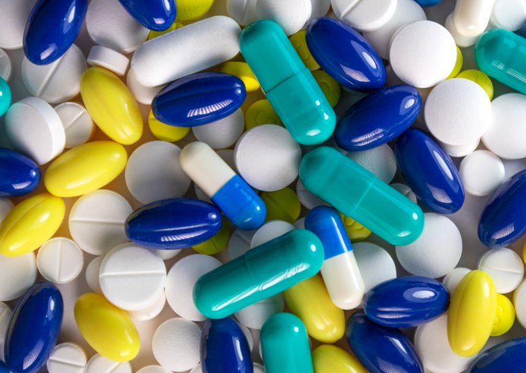 Various tablets, soft gels and capsules in white, blue and yellow