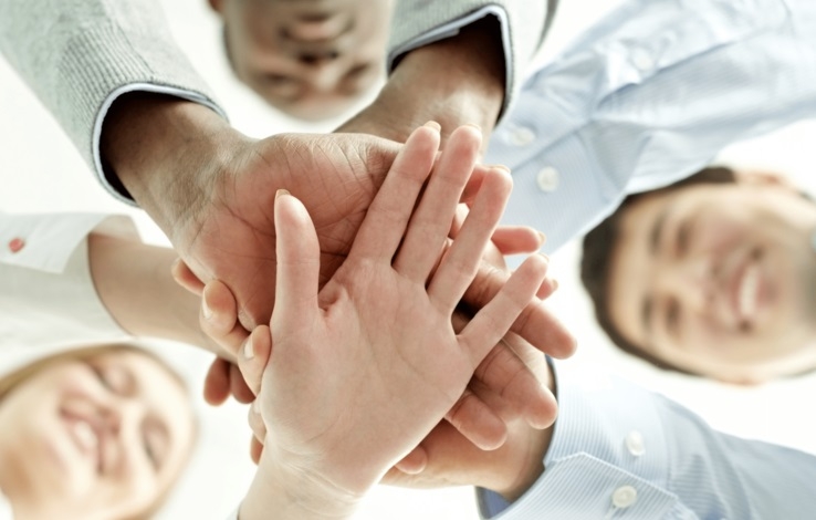 A group of happy people placing their hands on top of each other