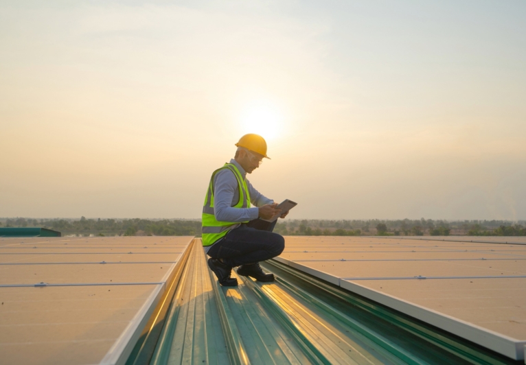 Industrial worker on a roof at sunset